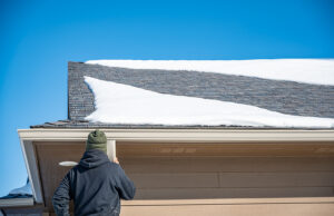 Contractor installing gutters on a home with snow on the roof